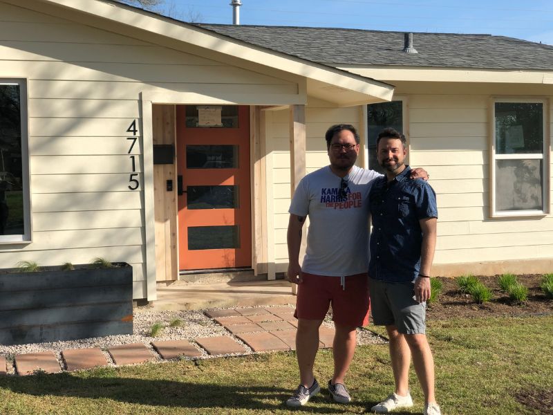 Gay couple standing in front of one-story renovated home in South Austin, TX