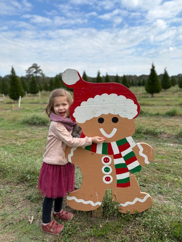 adoptive couples daughter hugging gingerbread man cutout at Houston, TX farm