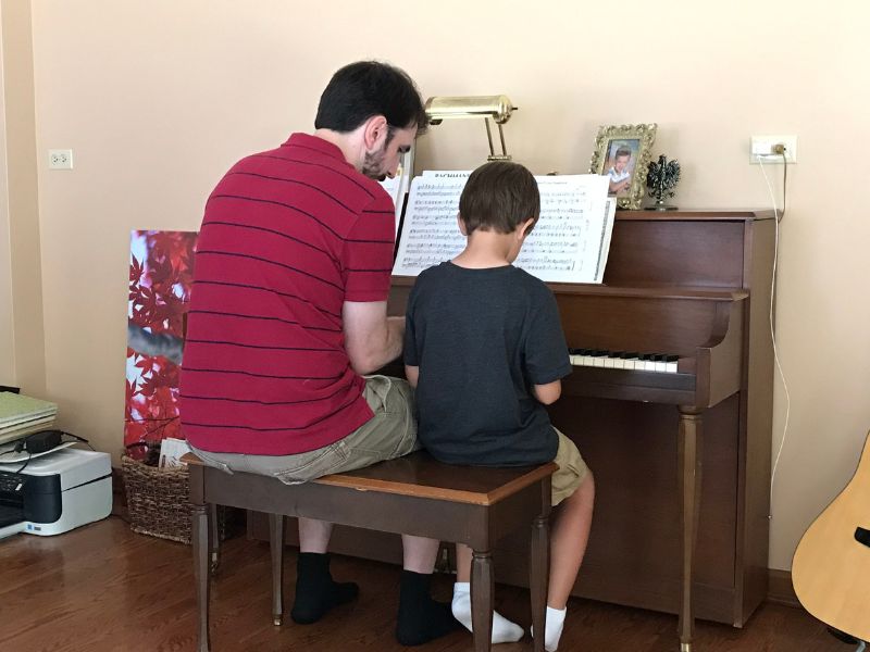 Adoptive dad Zac teaching piano to young child