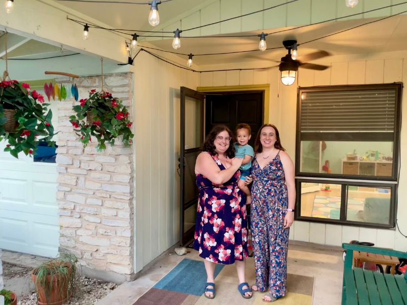 Jessica and Amanda, white adoptive moms, on the porch of their Austin, TX house.