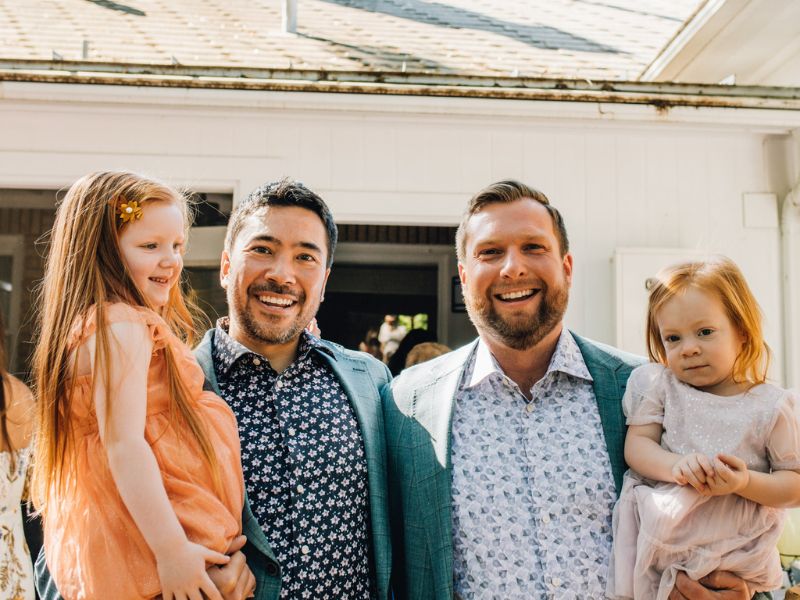 Gay couple that wants to adopt, holding nieces and smiling