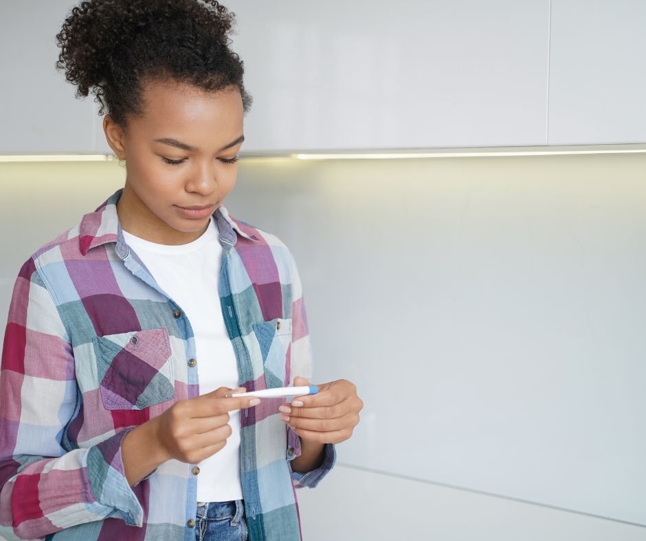 Teenage girl looking at positive pregnancy test