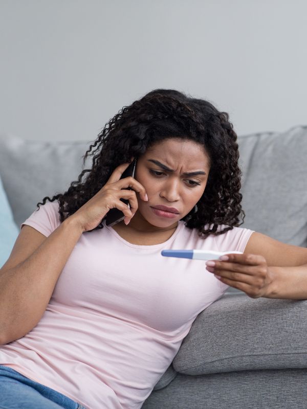 Woman with pregnancy test calling to learn how to give her baby up for adoption